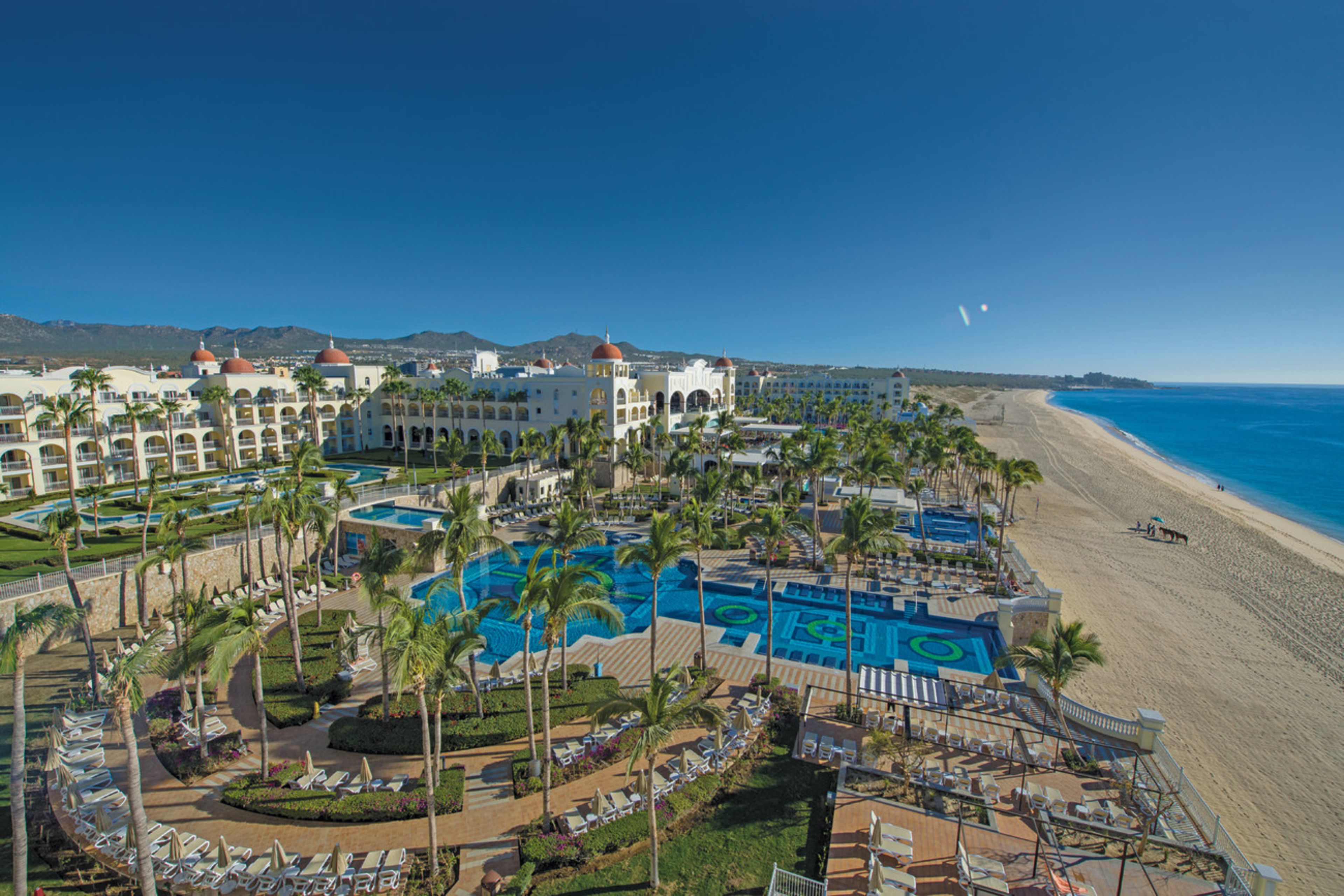 A resort with multiple swimming pools, palm trees, and a beach.