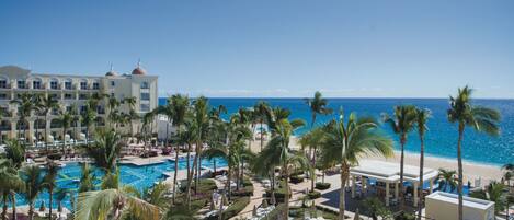 A resort with a pool, palm trees, and a beach view.