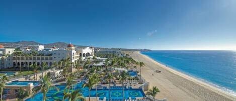 A resort with a large pool area, beach access, and a view of the ocean.