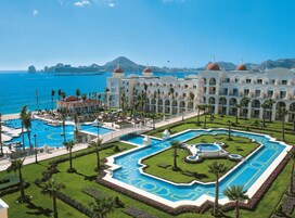 A resort with multiple swimming pools, a beach, and a large building with domed roofs.
