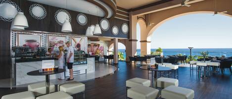 A modern bar area with a view of the sea, featuring a counter, seating, and decorative lighting.
