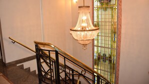 Una escalera con barandilla de metal negro y un candelabro colgando.