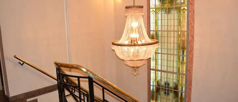 A staircase with a black metal railing and a chandelier hanging above.