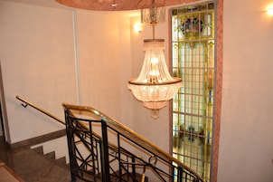 Uma escadaria com guarda-corpo de metal preto e um candelabro pendurado acima.