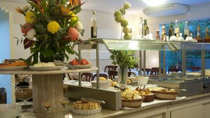 Montaje de bufé con diversos alimentos, un centro de mesa floral y una selección de botellas.