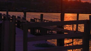 A sunset over a waterfront with a wooden dock and a street lamp. - Thames Inn & Marina (Groton)