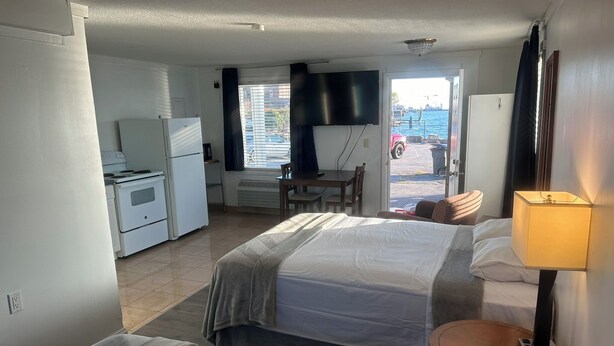 A hotel room with two beds, a kitchenette, a TV, and a view of the water. - Thames Inn & Marina (Groton)