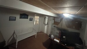 A hallway with a white bench, a door, and a bulletin board. - Thames Inn & Marina (Groton)