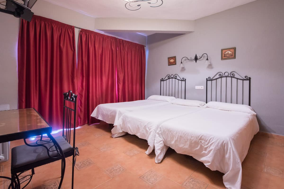 A room with two beds, a table, and a chair.