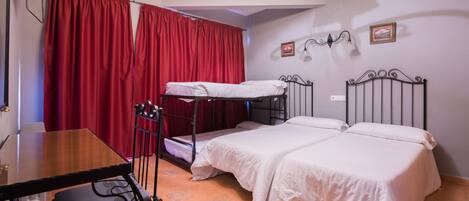 A room with a bunk bed, a desk with a chair, and a red curtain.