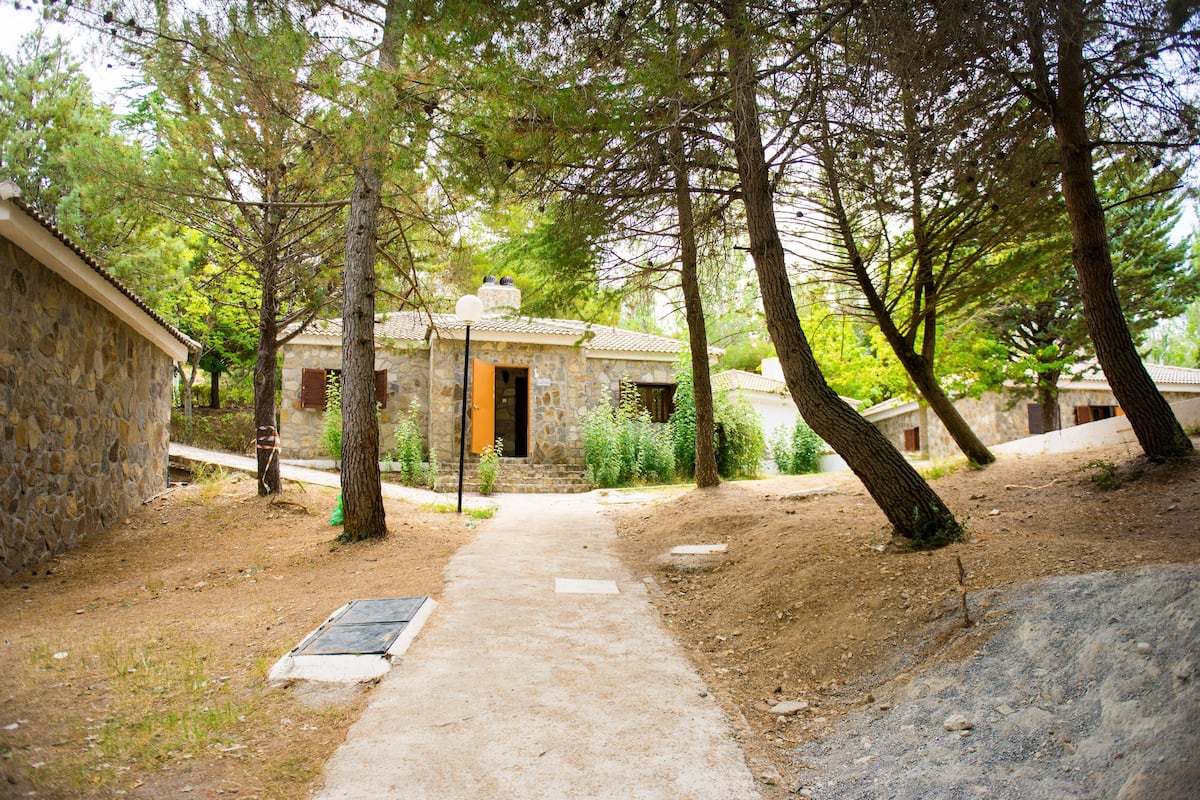 A stone building with a pathway leading to it, surrounded by trees.
