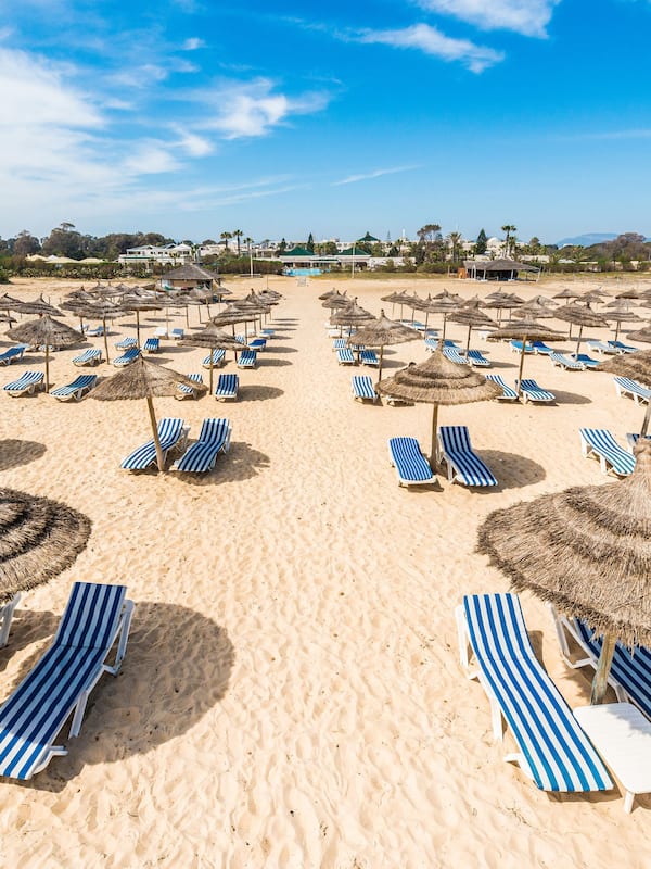 Am Strand, weißer Sandstrand, Liegestühle, Sonnenschirme