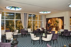 A hotel lobby with a seating area, large windows, and a view of the outdoors.