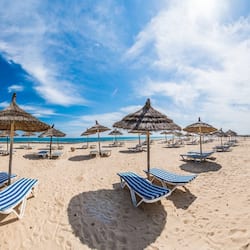 Am Strand, weißer Sandstrand, Liegestühle, Sonnenschirme