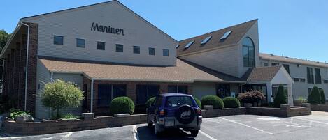 A building with a sign that reads 'Mariner' and a parking lot with a vehicle.