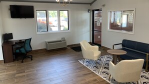 Une chambre moderne équipée d’un bureau, d’un fauteuil de bureau, d’un canapé et d’un tapis à motifs.