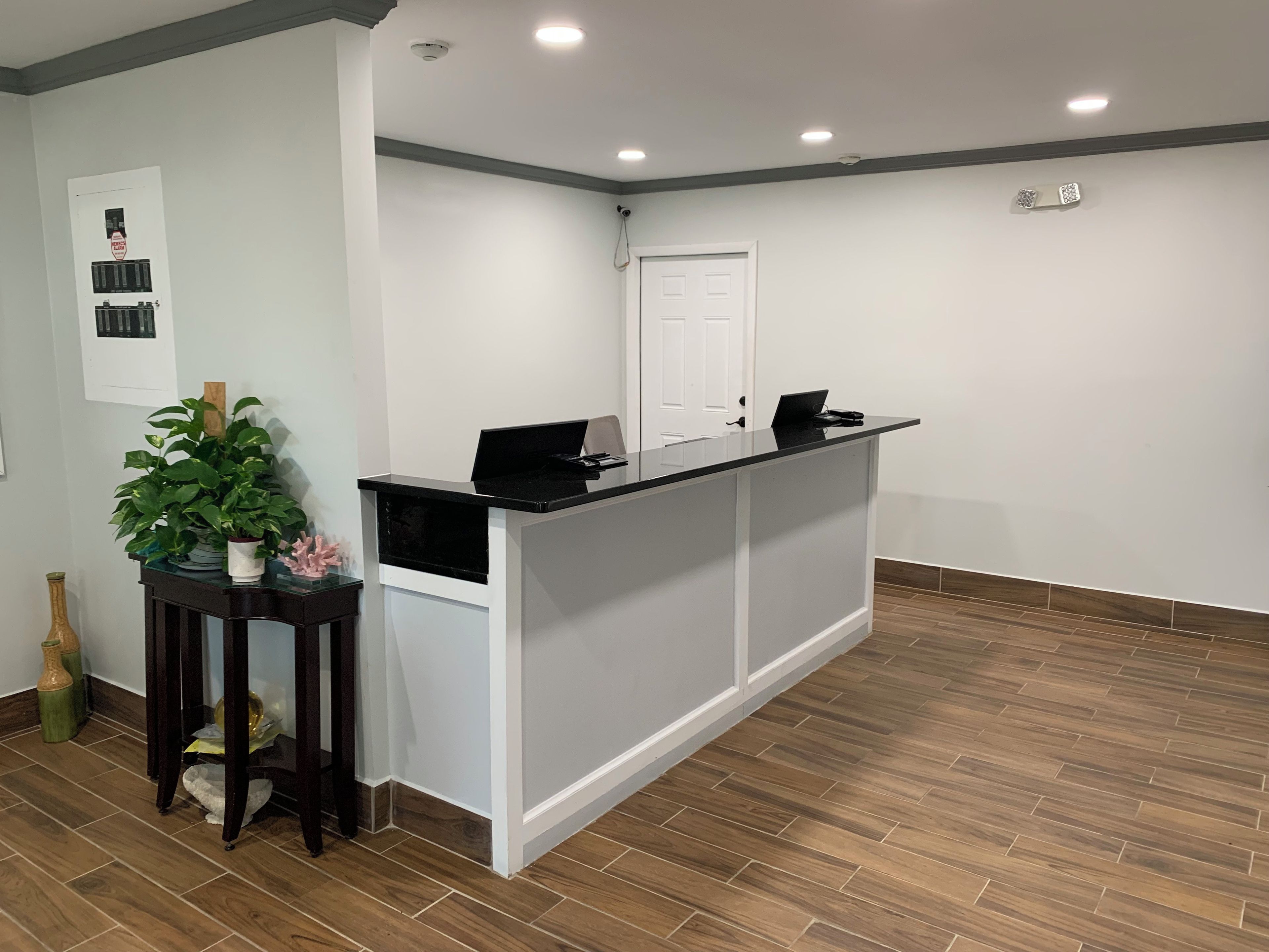 A reception desk with a laptop, a potted plant, and a small table with decorative items.