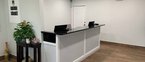 A reception desk with a laptop, a potted plant, and a small table with decorative items.