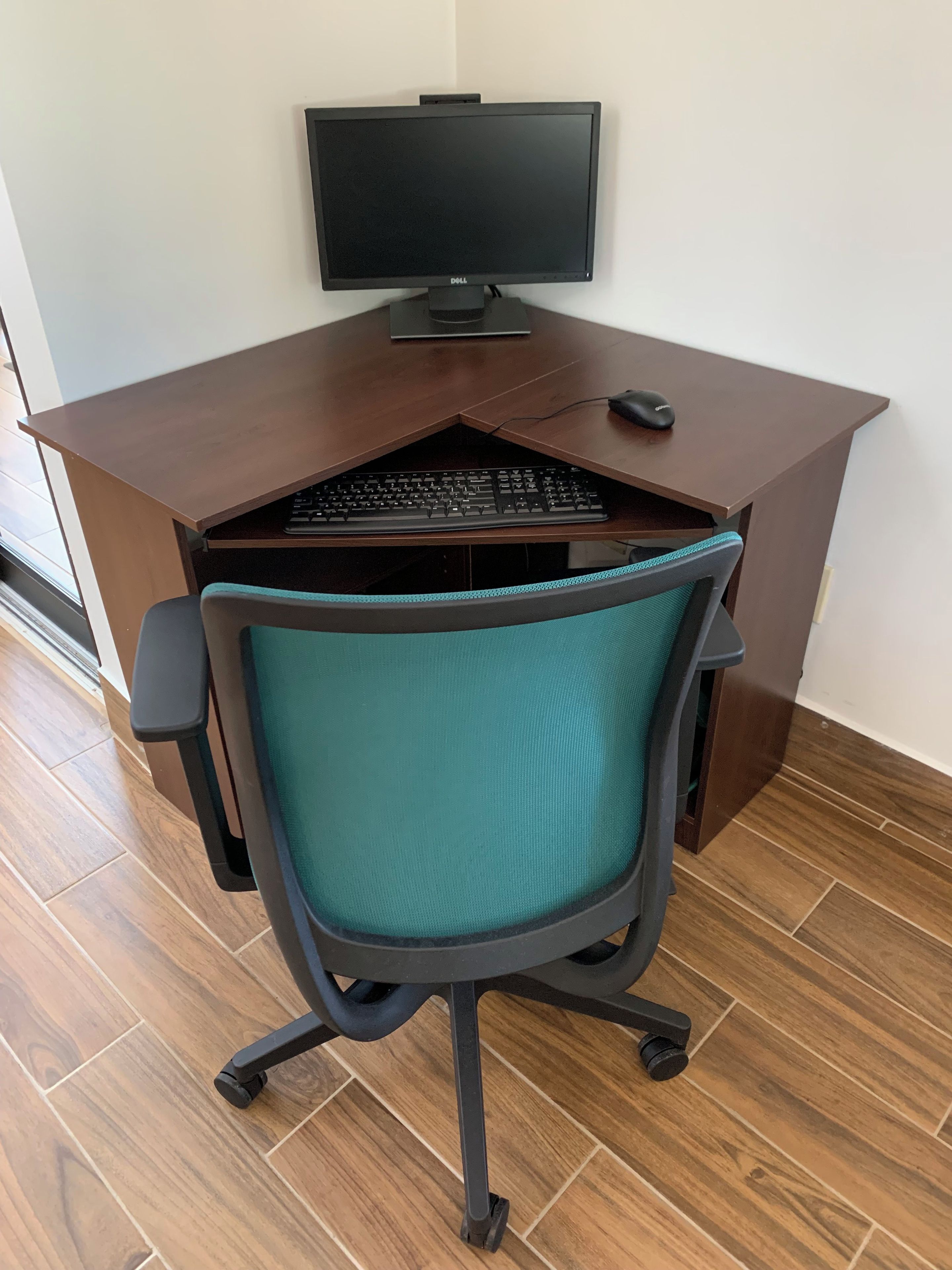 A wooden desk with a computer monitor, keyboard, and mouse.