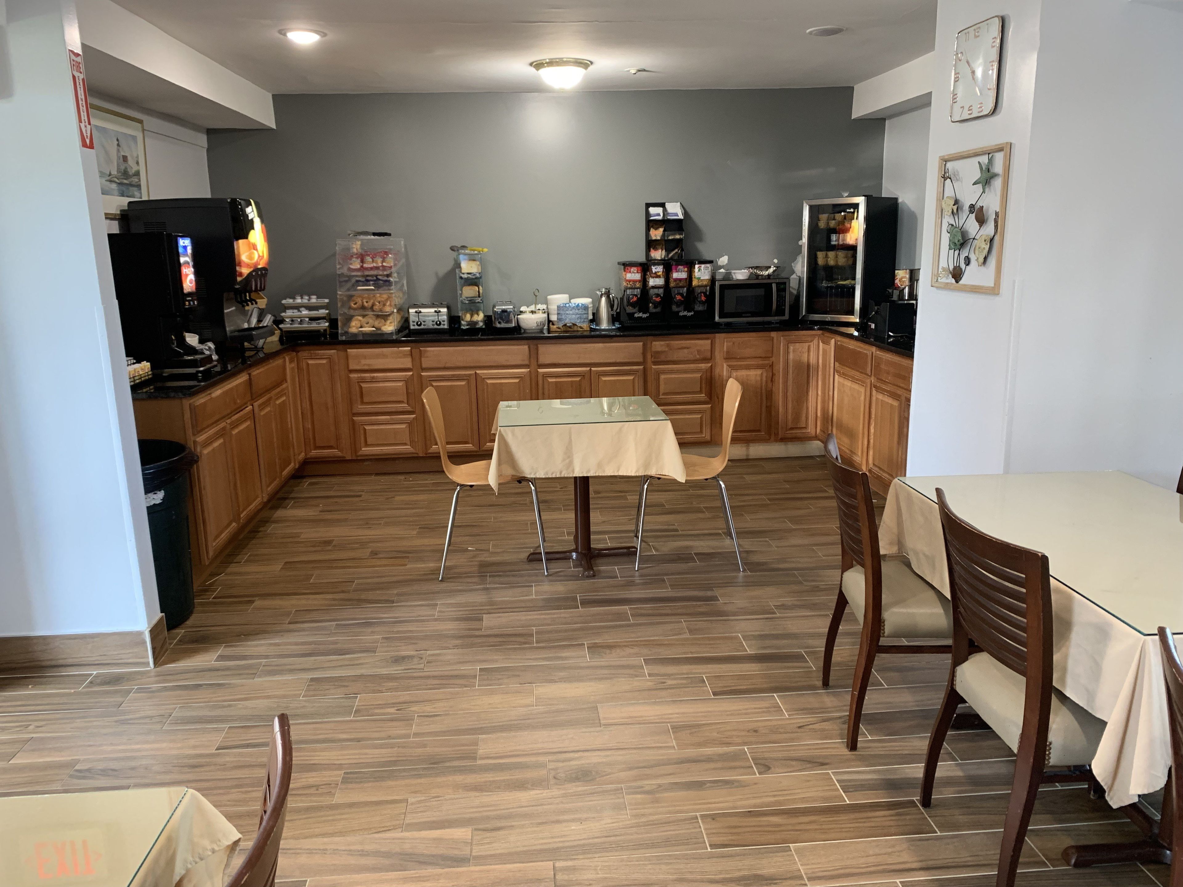Una cocina con armarios de madera, una mesa de comedor, sillas, un refrigerador y un microondas.