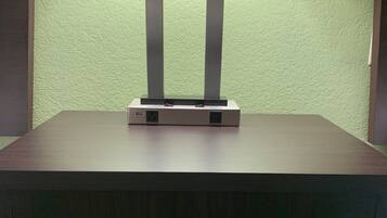 Una mesa con una lámpara y un distribuidor de corriente, un cajón y una pared verde con textura.