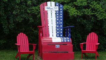 A red Adirondack chair with a flag design, a sign reading 'The Mariner Lodge Cape Cod,' and another chair beside it.