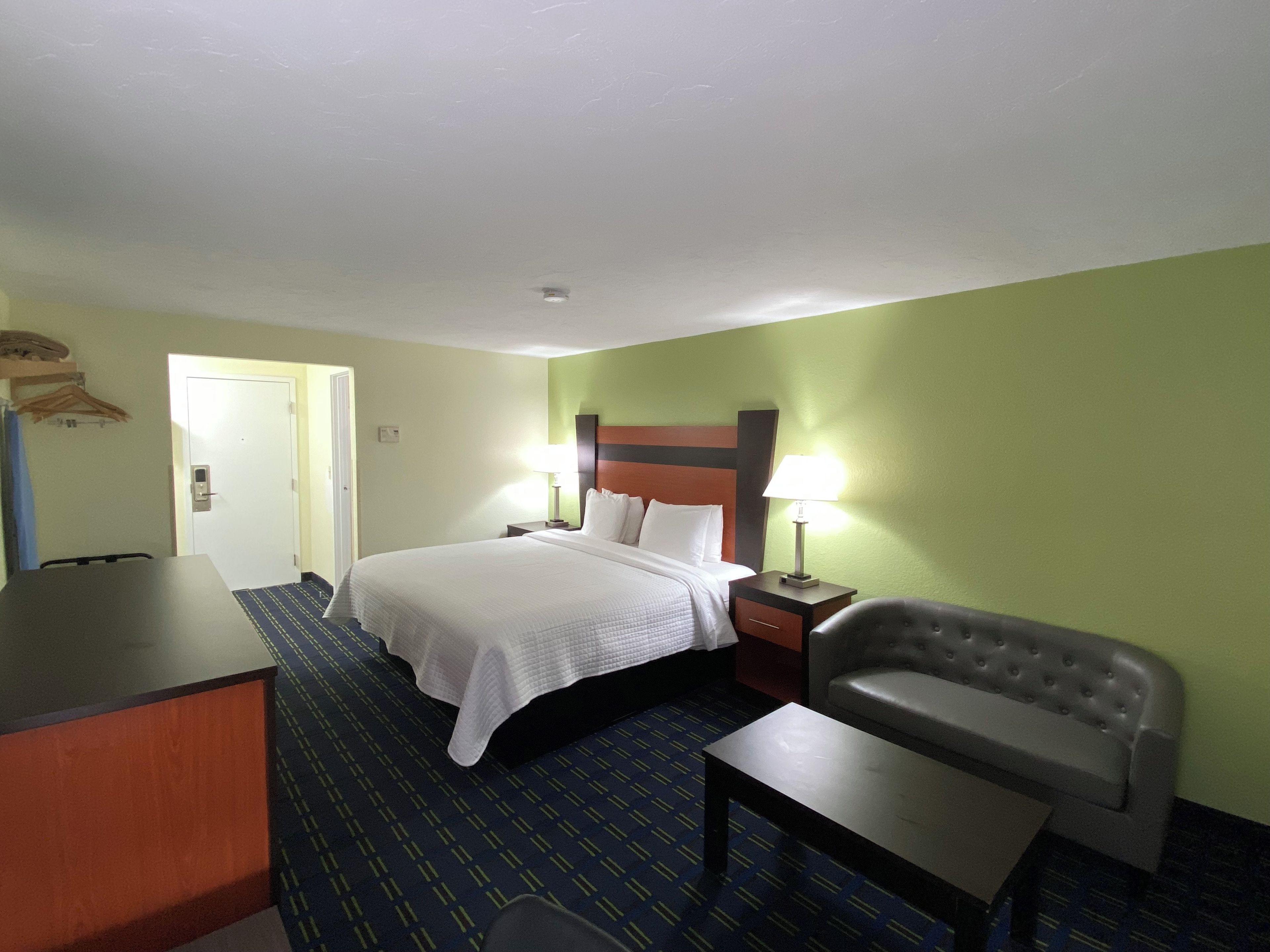 A hotel room with a bed, bedside tables, a desk, and a chair.