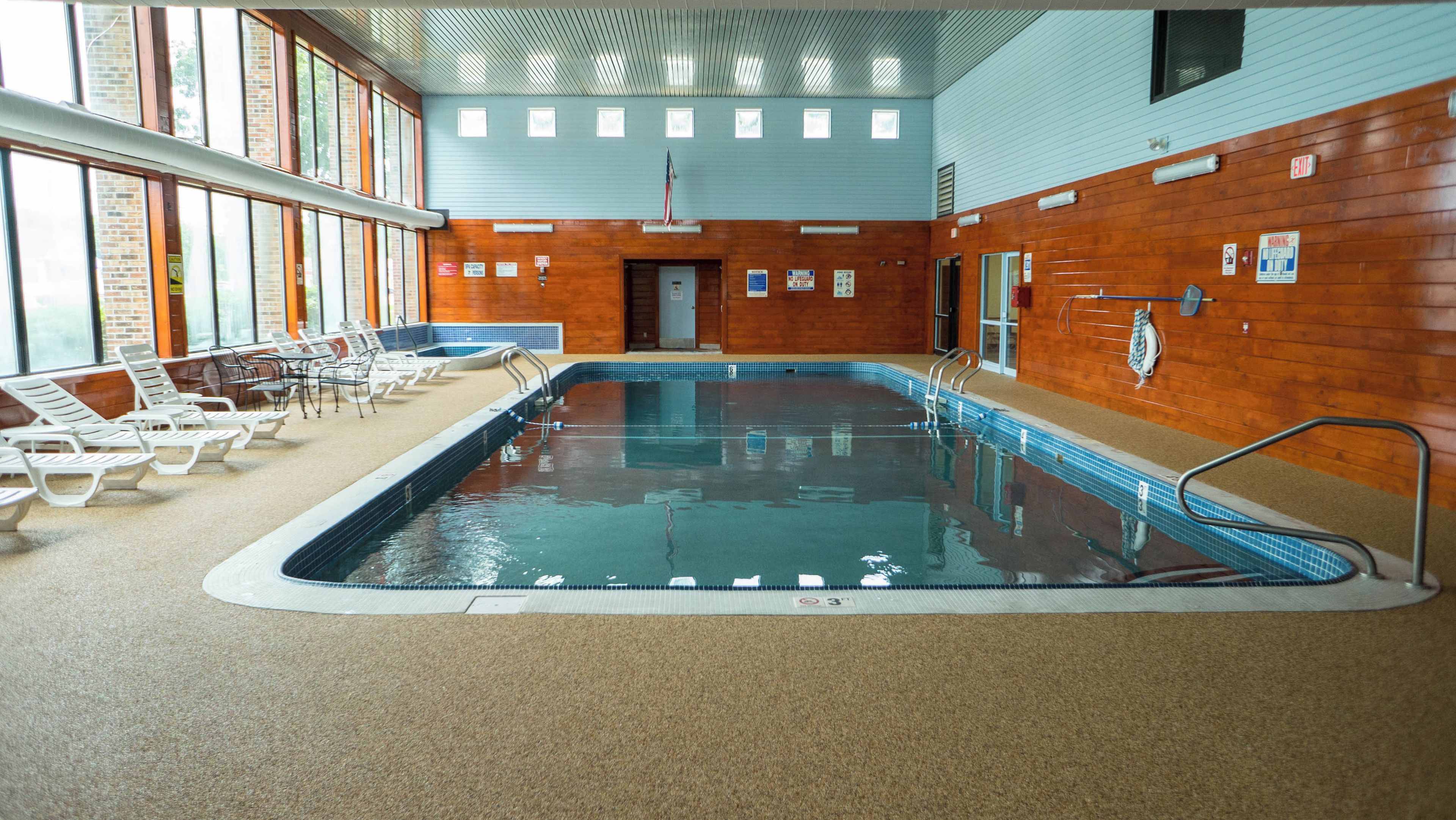 An indoor swimming pool with lounge chairs and a wooden wall.