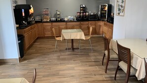 Une cuisine avec des meubles de rangement en bois, une table à manger avec des chaises, un réfrigérateur et un four à micro-ondes.