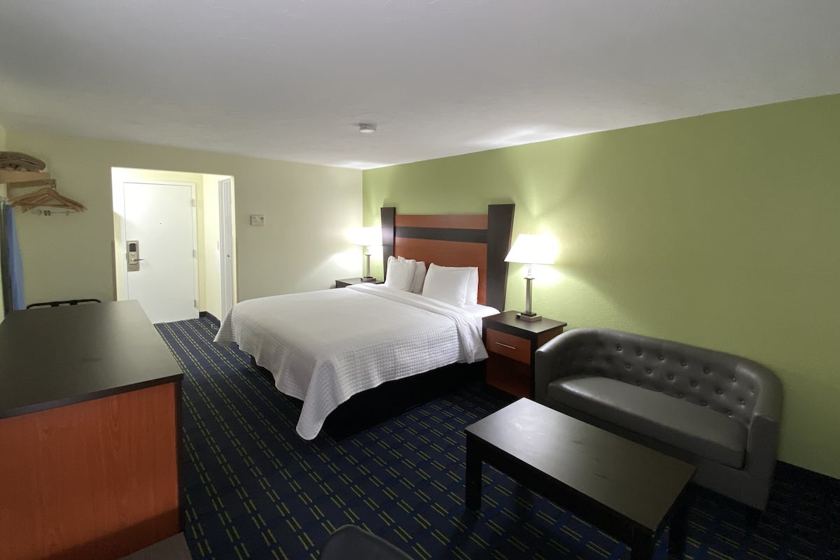 Ein Hotelzimmer mit einem Bett, Nachttischen, einem Schreibtisch und einem Sessel.
