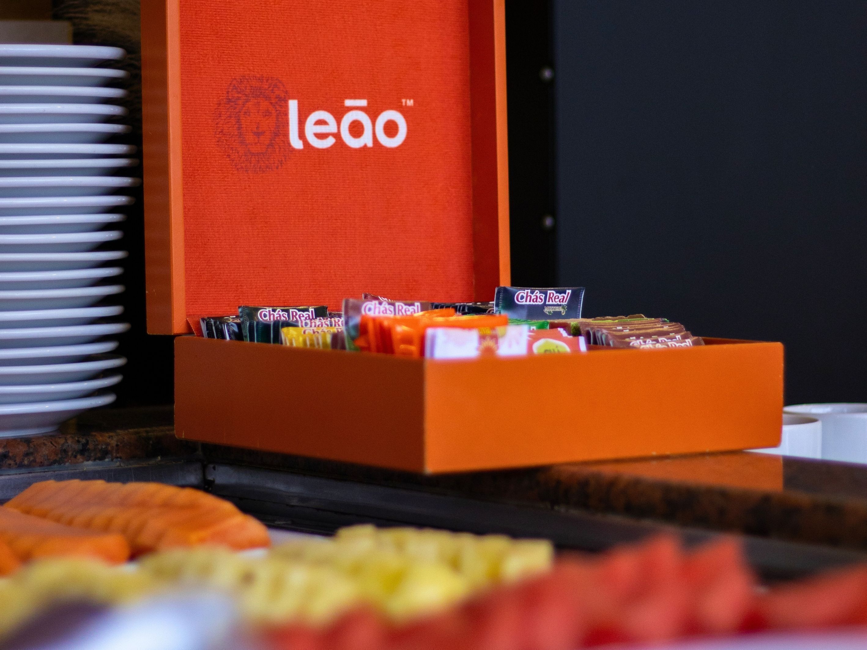 Un bufé de desayuno con diversas opciones de bocadillos y una caja naranja con el logo de la marca al fondo.