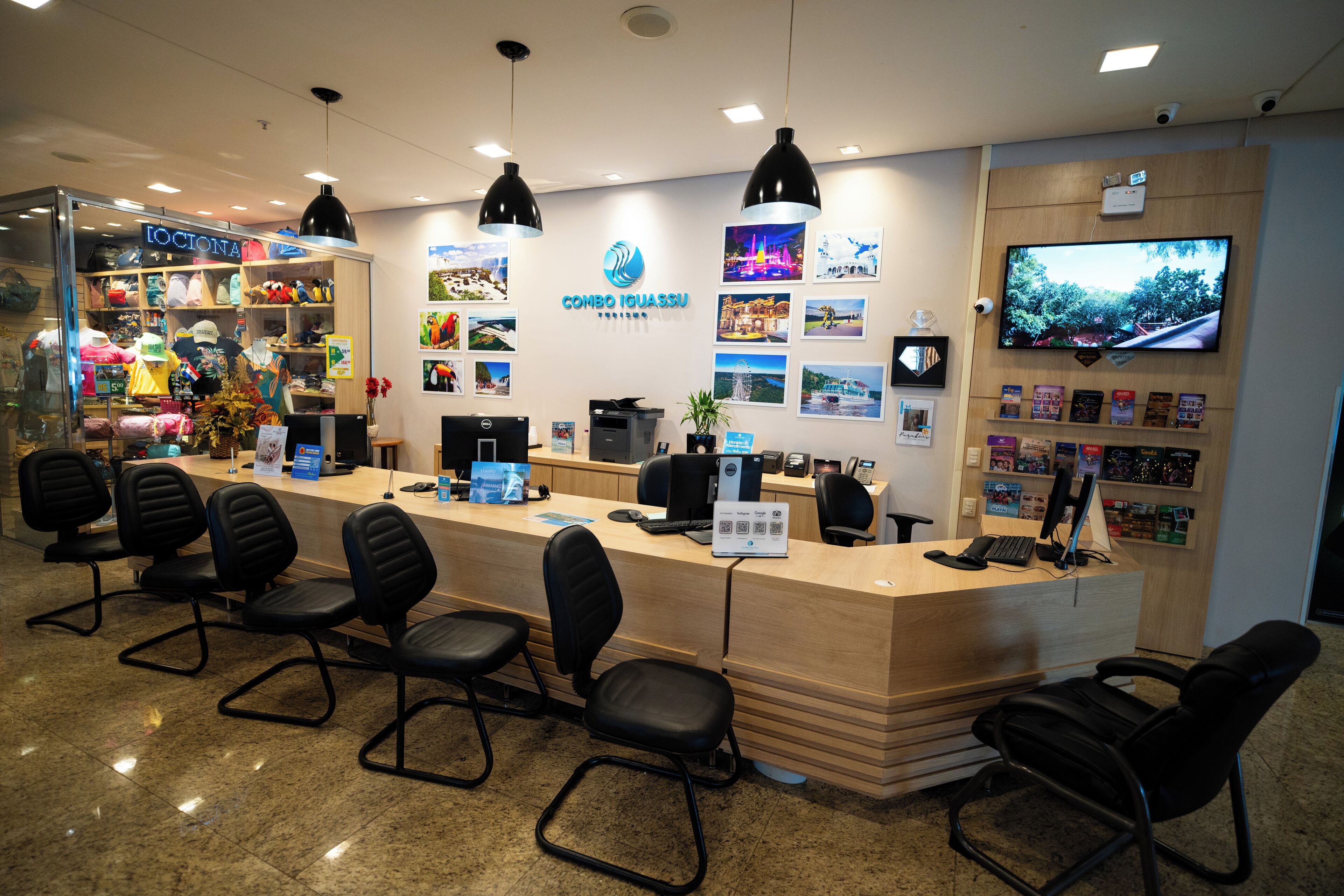 A reception desk with black chairs, a computer, and a TV on the wall.