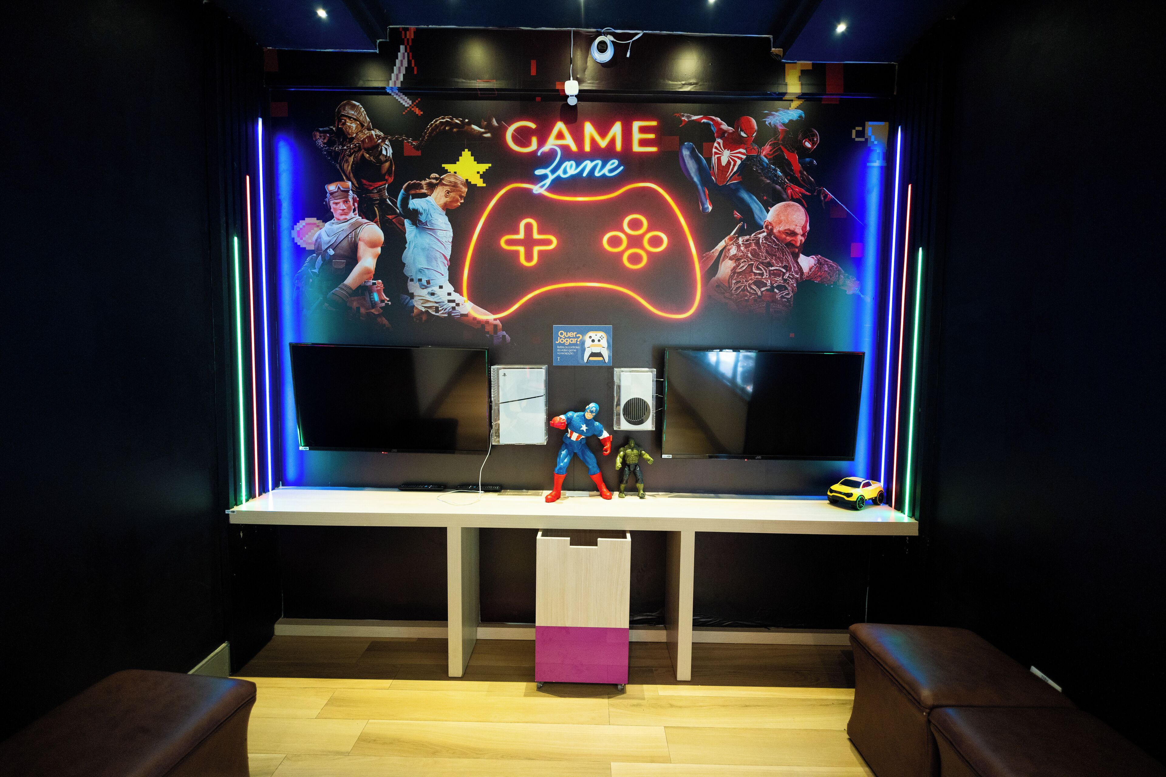A gaming-themed room with a neon sign, action figures, and a large screen.
