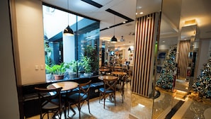 Un café moderno con pared de vidrio, mobiliario de madera y un árbol de Navidad.