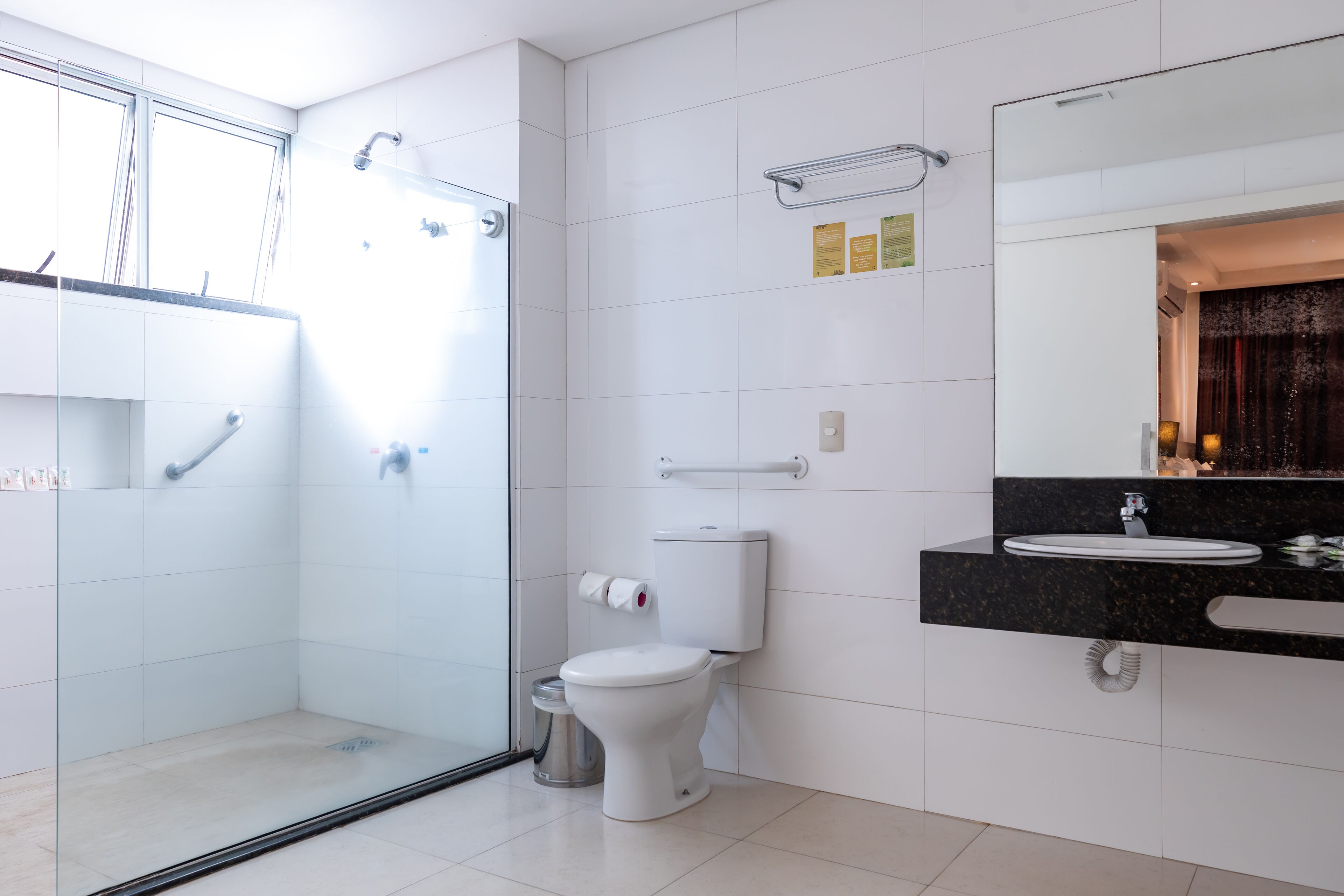Un baño moderno con ducha acristalada, inodoro e lavamanos con encimera negra.
