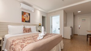 Una habitación de hotel con una cama grande, un cuadro en la pared y una puerta que da al baño.
