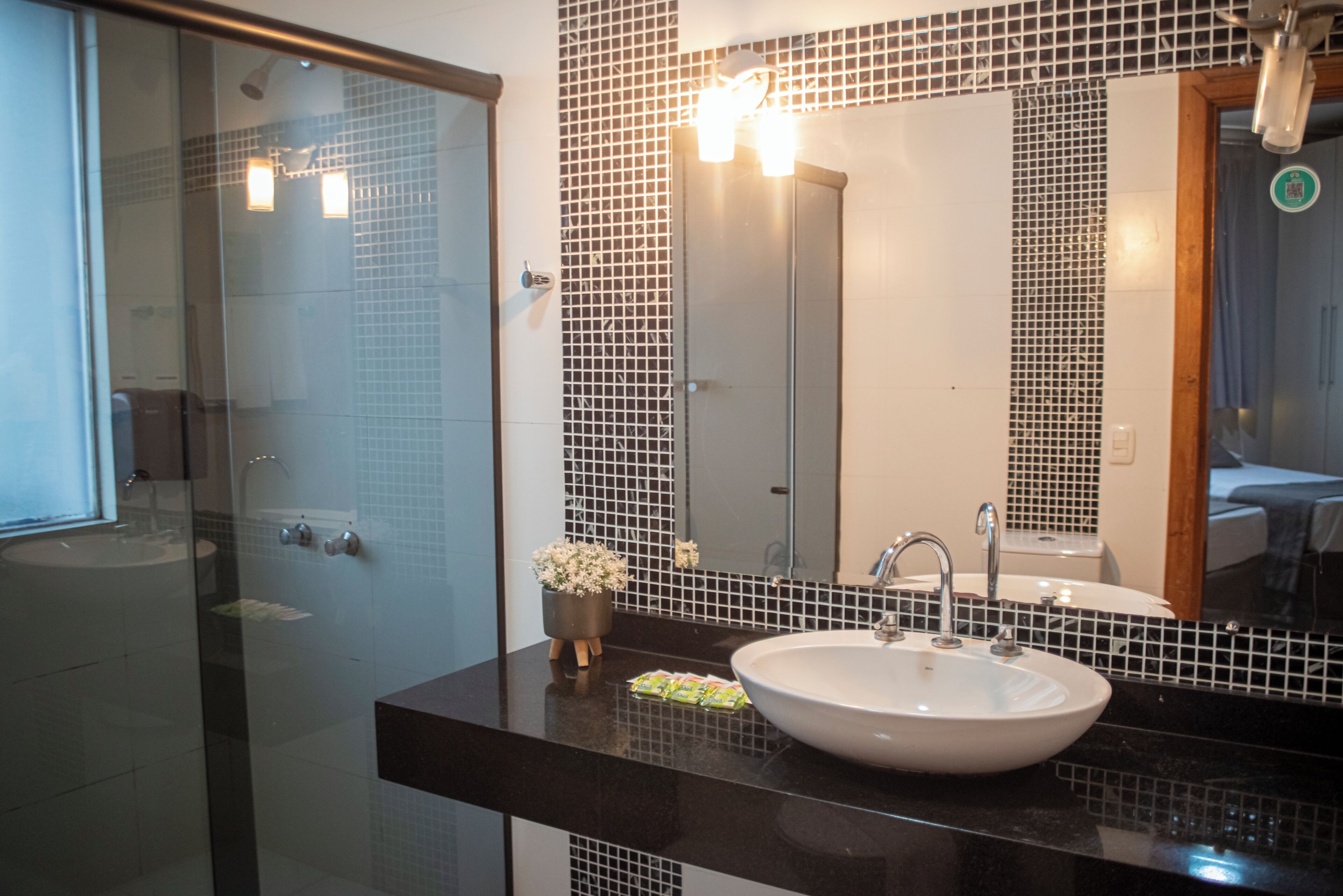 Un baño moderno con cabina de ducha de vidrio, un lavabo blanco y un espejo grande.