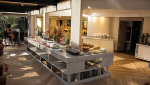 A modern kitchen with a marble island, wooden flooring, and a seating area with chairs. - Hotel Portinari Centro (Foz do Iguaçu)