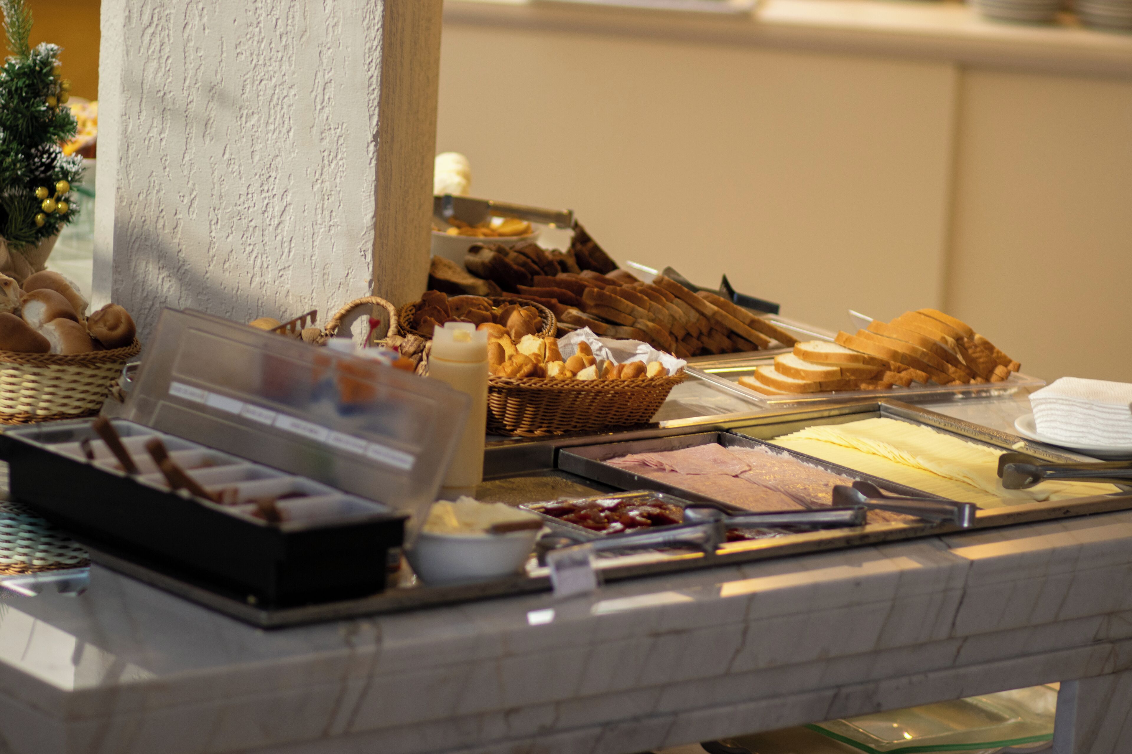 Un buffet proposant une variété de plats, notamment du pain, des viennoiseries et des desserts.