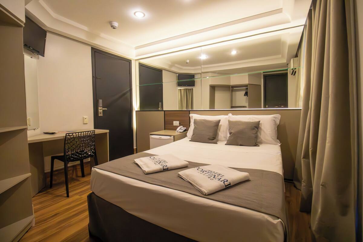 Een moderne hotelkamer met een opgemaakt bed, een bureau en een stoel.