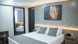 A modern hotel room with a large bed, bedside tables, a desk, and a mirror. - Hotel Portinari Centro (Foz do Iguaçu)