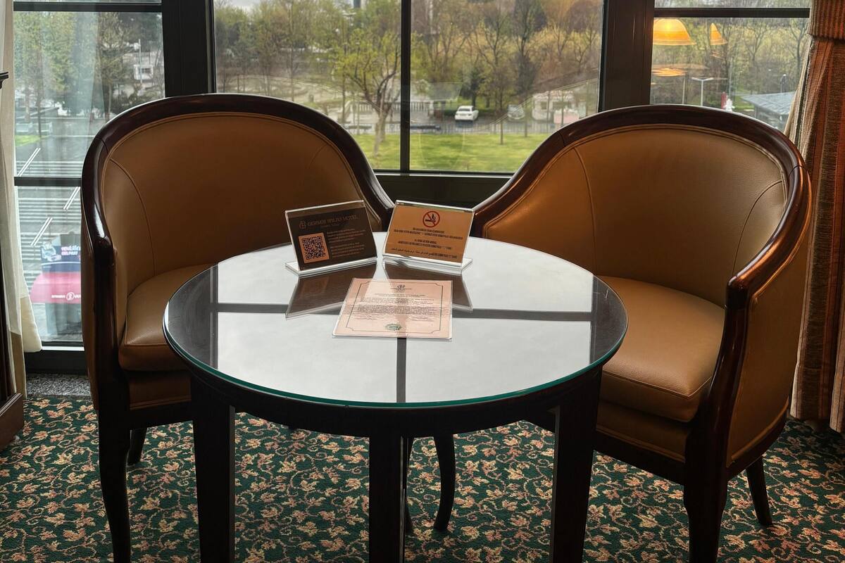 A room with a large arched window, two leather chairs, a small round table, and informational cards on the table.