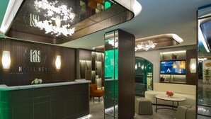 Eine moderne Hotelhalle mit einer Rezeption, einer Sitzecke und einem großen Bildschirm, der eine Stadtansicht zeigt.