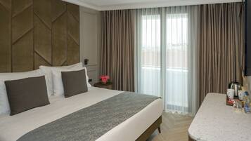 A hotel room with a large bed, a small table with a coffee maker, and a view of the city through the window.