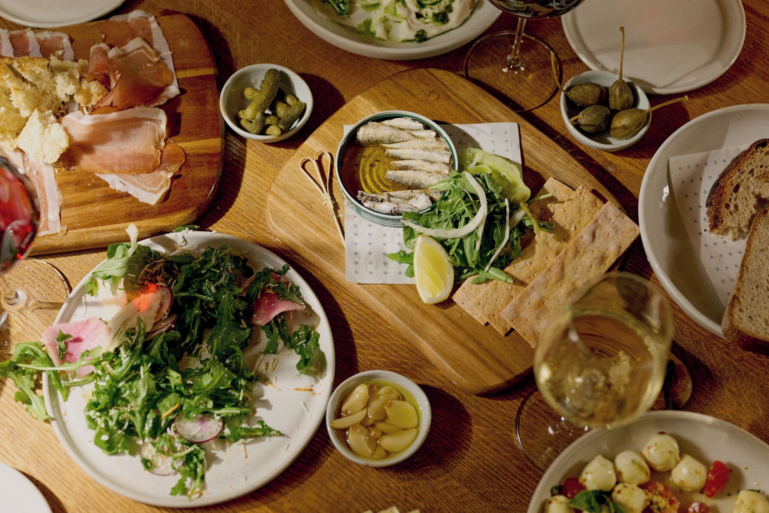 Une table à manger avec différents plats, notamment une salade, du pain et une assiette de cornichons.