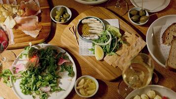 Une table à manger avec différents plats, notamment une salade, du pain et une assiette de cornichons.