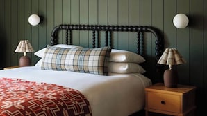 A bed with a patterned blanket, a headboard, two bedside lamps, and a nightstand with a drawer. - The Alpine House (Jackson)