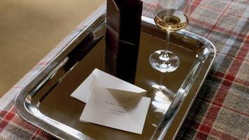 A tray with a glass of wine, a menu, and a card on a checkered tablecloth.