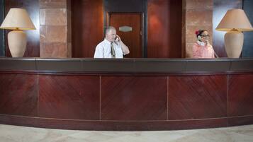 A reception desk with a marble wall, a wooden door, and two lamps.