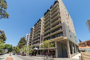 A multi-story hotel with balconies, a ground-level restaurant, and a clear blue sky. - Starwest Apartments Alderney on Hay (East Perth)